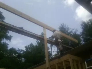 Carpenter setting a ridge beam over a new addition frame — Ice Dam Removal by Roofing Brothers in Garvin