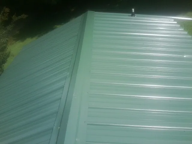 New green metal panels meeting at the ridge of a roof — Flat Roof Repair work by our crew in Garvin