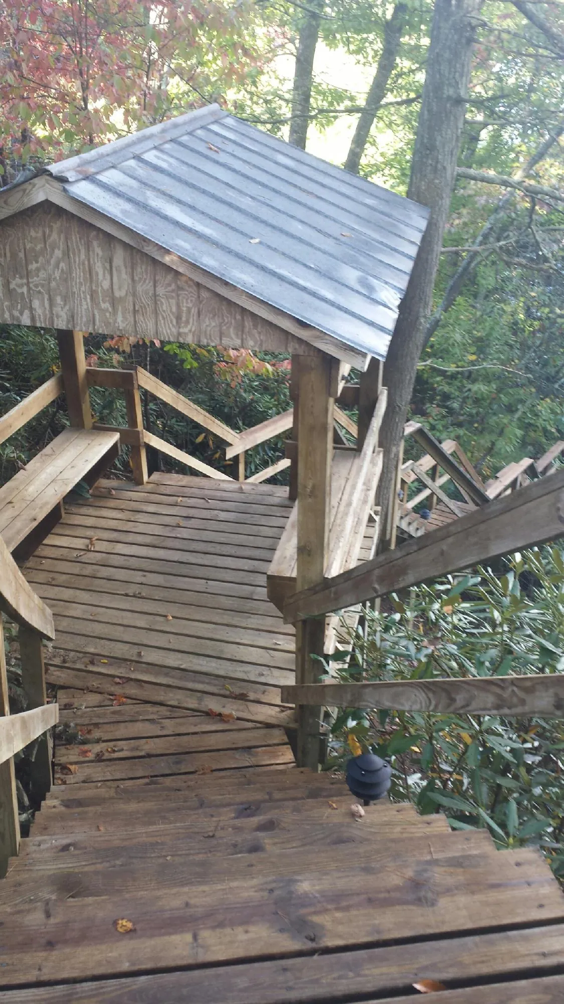 Metal roofed shelter over wooden steps on a wooded walkway — Skylight Repair & Installation work by our crew in Garvin