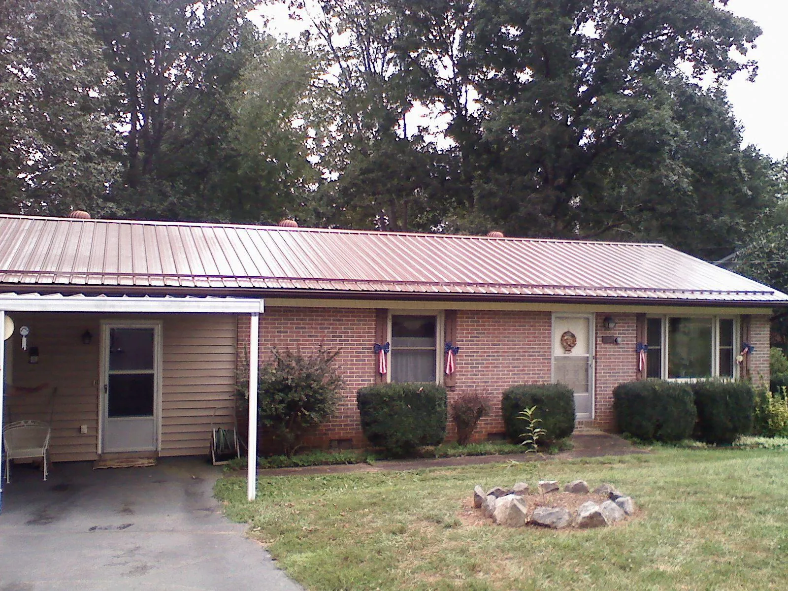 Bronze metal roof and carport on a brick ranch home — Roof Repair work by our crew in Garvin